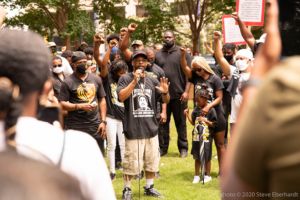 Family members of Rayshard Brooks speak to gathered protesters using a microphone