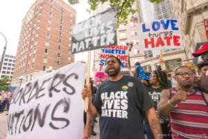 Protesters holding signs, including "Love trumps Hate" and "Black Lives Matter"