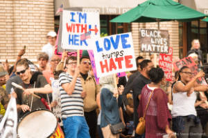 Protesters holding signs, including "Love trumps Hate" and "I'm with her"