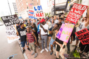 Protesters holding signs, including "Build a wall around Trump Tower" and "Black Lives Matter"