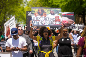 A protester carries a sign that reads, "Justice for Alton Sterling"