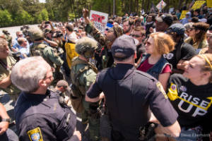 A crowd of protesters stands in front of a line of police