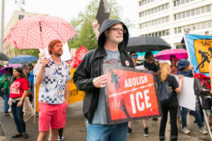 Protesters with signs and umbrellas, "Abolish ICE"