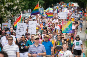 Protesters march with signs, including "50 yrs later we are still here queer & fighting for 4 equality" and "Do no harm Take no shit"