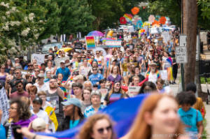 Protesters march, some with signs, many with rainbow flags