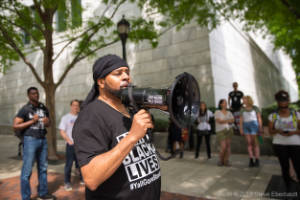 A man holding a megaphone speaks to protesters