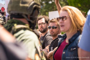 A group of protesters stand in front of a line a police