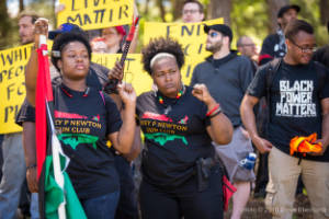 Two protesters wear "Huey P. Newton Gun Club" t-shirts