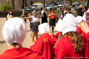 Protester infront of others dressed as characters from Handmaiden's Tale