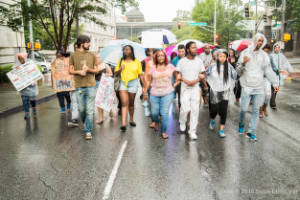 Protesters march through the street in the rain