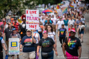 Protesters march with signs, including "I love my trans nonbinary son!"