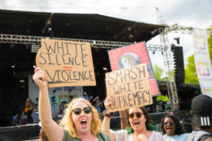 A protester holds a sign that reads, "White silence = violence"