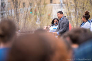 A man stands at a podium addressing the crowd