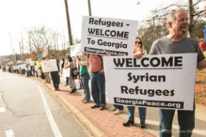 People holding signs in support of immigration stand along a street.