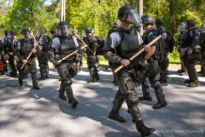 A group of police officers carry wooden batons
