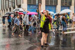 A woman stops traffic for protesters in the street