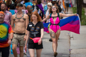 Protester in pink bathing suit with bisexual pride flag