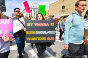A protester holds a sign that reads, "My vagina is more regulated than your gun"