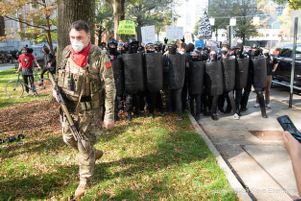 A counter-protester carries a rifle in front of a group of counter-protesters