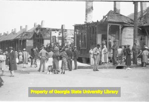Bystanders inspect three fire damaged houses, Atlanta, Georgia, circa late 1930s or early 1940s