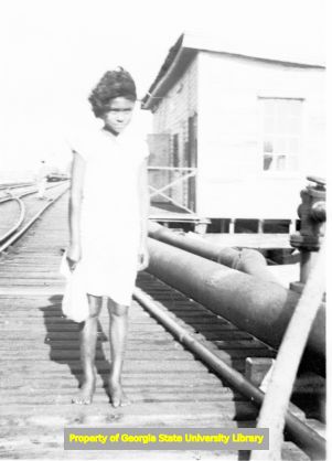 African-American girl walking on railroad tracks, circa late 1930s or early 1940s