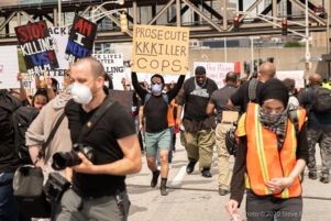 A protester holds up a sign reading 'Prosecute KKKiller Cops'