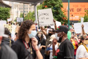 A protester holds up a sign reading 'Silence is NOT an Option... #BlackLivesDoMatter'