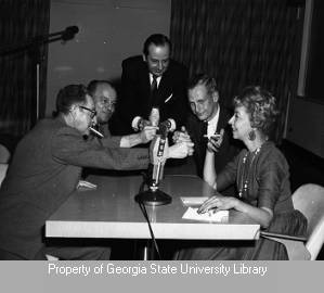 Four men offering to light a woman's cigarette during the program Witness