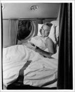 Woman laying in hospital bed on Eastern Air Lines Super Constellation aircraft, 1951