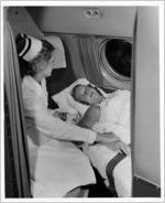 Nurse attending woman in hospital bed aboard Eastern Air Lines Super Constellation aircraft, 1951