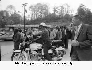 Motorcycle policeman with protesters on Northside Drive, during the Atlanta sanitation workers strike, Atlanta, Georgia, April 13, 1970.