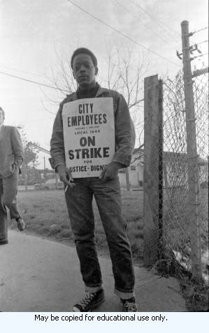 AFSCME Local 1644-led sanitation strike, Atlanta, Georgia, March 1970. These photographs are taken outside the City of Atlanta Construction Department office and warehouse (110-111 Hill Street). Protestors are apparently attempting to block strikebreakers from crossing the picket-line and entering the office area. The photograph series is labeled "Garbage Strike."
