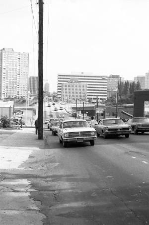 Man standing on Piedmont Avenue looking at approaching traffic, 1969