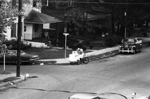 Ice-cream man riding his cart through a neighborhood, 1969