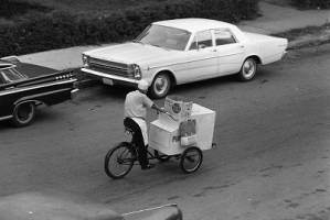 Ice-cream man riding his cart through a neighborhood, 1969
