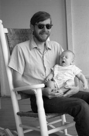 Tom Coffin holding his son in a rocking chair, 1969