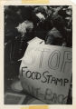 People listening to speaker, sign by aisle reads "Stop Food Stamp Cut-Back"