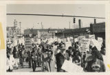 Protesters march down a street with signs