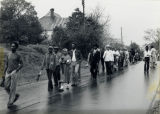 Protestors walk down street in the rain