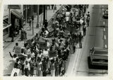 Protesters walk down street with signs, "Fight Rising Unemployment", "Fight Rising Prices Now", "Stop the War on the Poor"