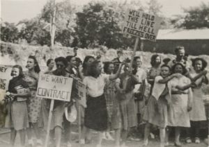Women protest with signs, "We want a contract" and "We'll hold this line till Hell freezes over"