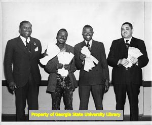 Four African-American union members pose with back pay checks