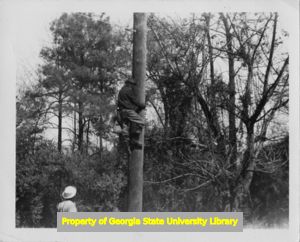 An electrical lineman climbs a utility pole