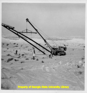 Large crane picking up H-frame power line poles