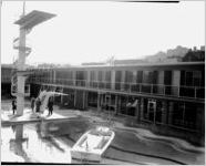 Speedboat in the Heart of Atlanta Motel swimming pool; men modeling winter clothing standing under high-dive board. Image for an advertising campaing conducted by the Charles A. Rawson and Associates advertising and public relations firm, at the Heart of Atlanta Motel, Atlanta, Georgia, February 27, 1960.