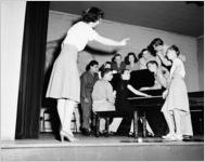 Soldiers, Sailors, and USO Hostesses singing along to a piano, Atlanta, Georgia, 1946.