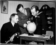Three men examining a small world globe, photo commissioned by DeKalb New Era