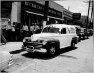 WBGE radio mobile unit automobile, parked outside the Buckhead Department Store. Reporter is interviewing woman on sidewalk, East Point, Georgia, May 18, 1948. Photo commissioned by Eastern Air Lines.