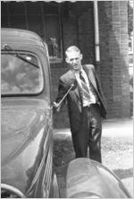 Employee of Eugene Harris, a cleaning company located in Midtown, standing outside of their warehouse, Atlanta, Georgia, 1930s