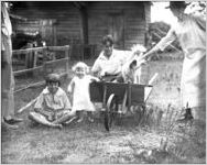Family on a wheel barrow in a farm yard